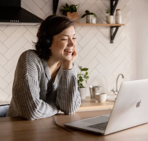 Feminine presenting person, smiling, having a video call via laptop